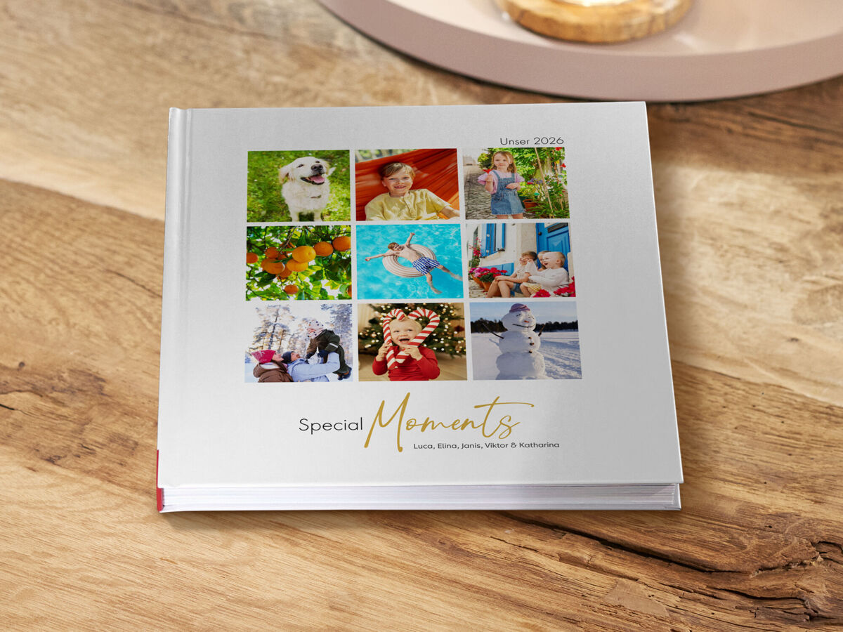 Auf einem Holztisch liegt ein weißes Fotobuch mit dem Titel „Special Moments“ und einer Collage aus neun persönlichen Familienfotos.